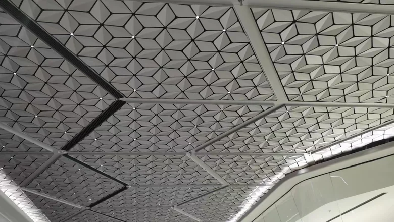 Suspended aluminum ceiling of pressed 3D panels with a raking linear light detail