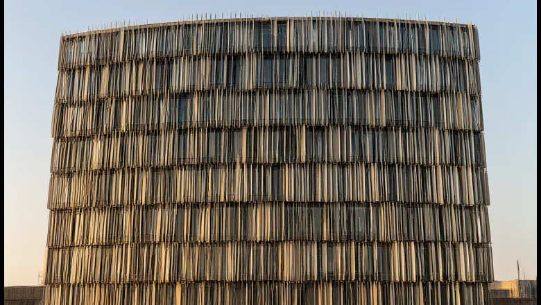Kinetic facade cost: wind-driven aluminium louvre screen on a commercial tower at sunset