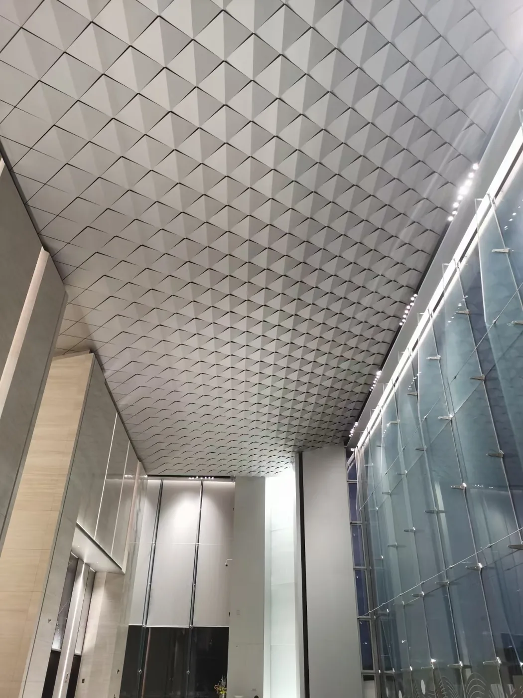Diamond-folded aluminium ceiling in a double-height entrance hall